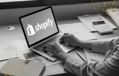 hands typing on laptop with shopify logo displayed on the screen